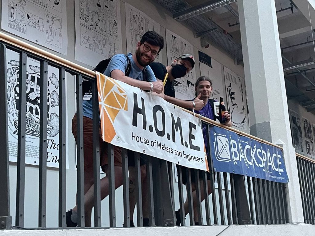 Ein Bild eines H.O.M.E.-Banners mit den H.O.M.E.-Menschen, die dieses gerade aufgehängt haben.